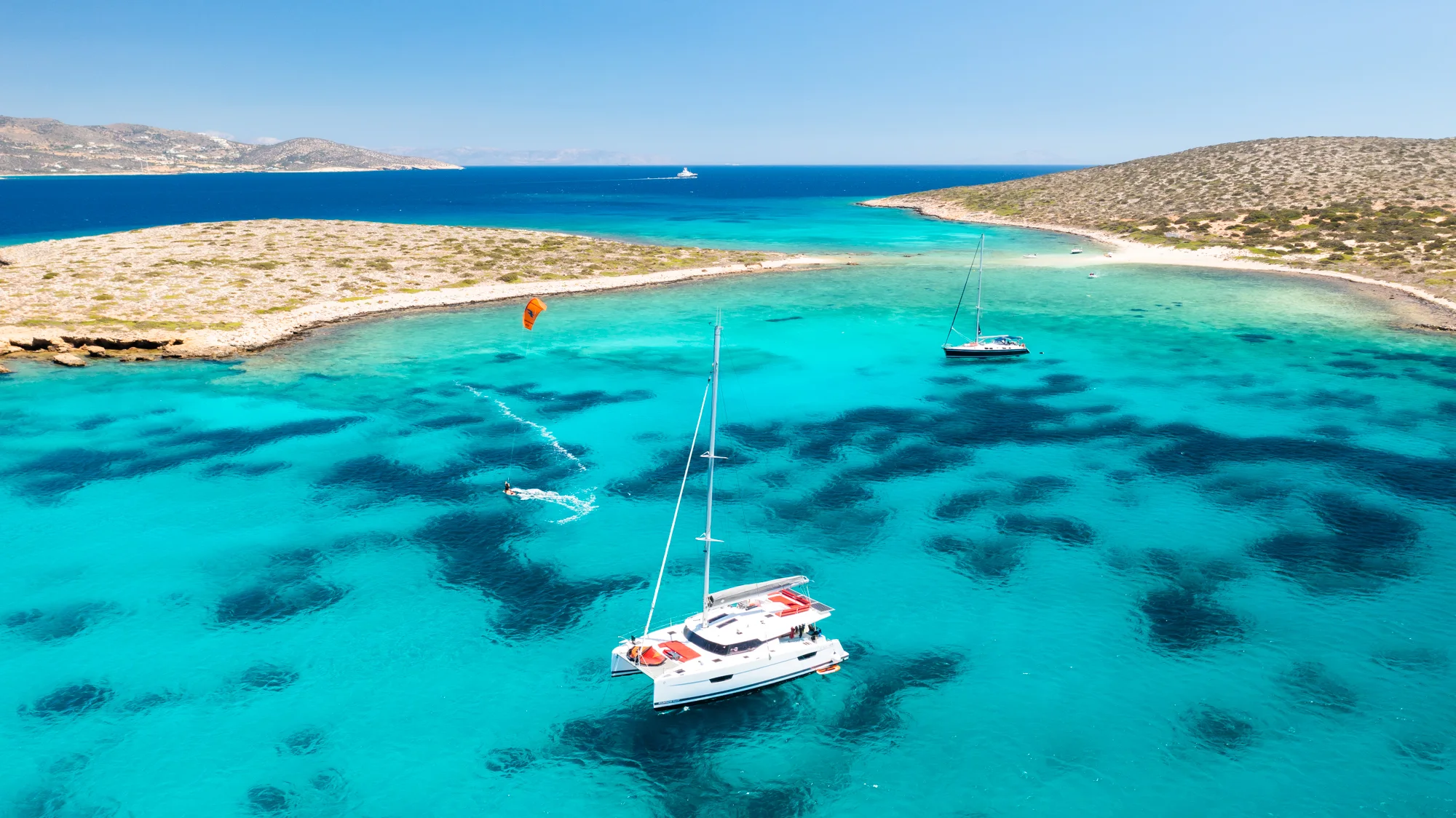 Aerial view of Makani anchored off a remote Cyclades island in clear water.