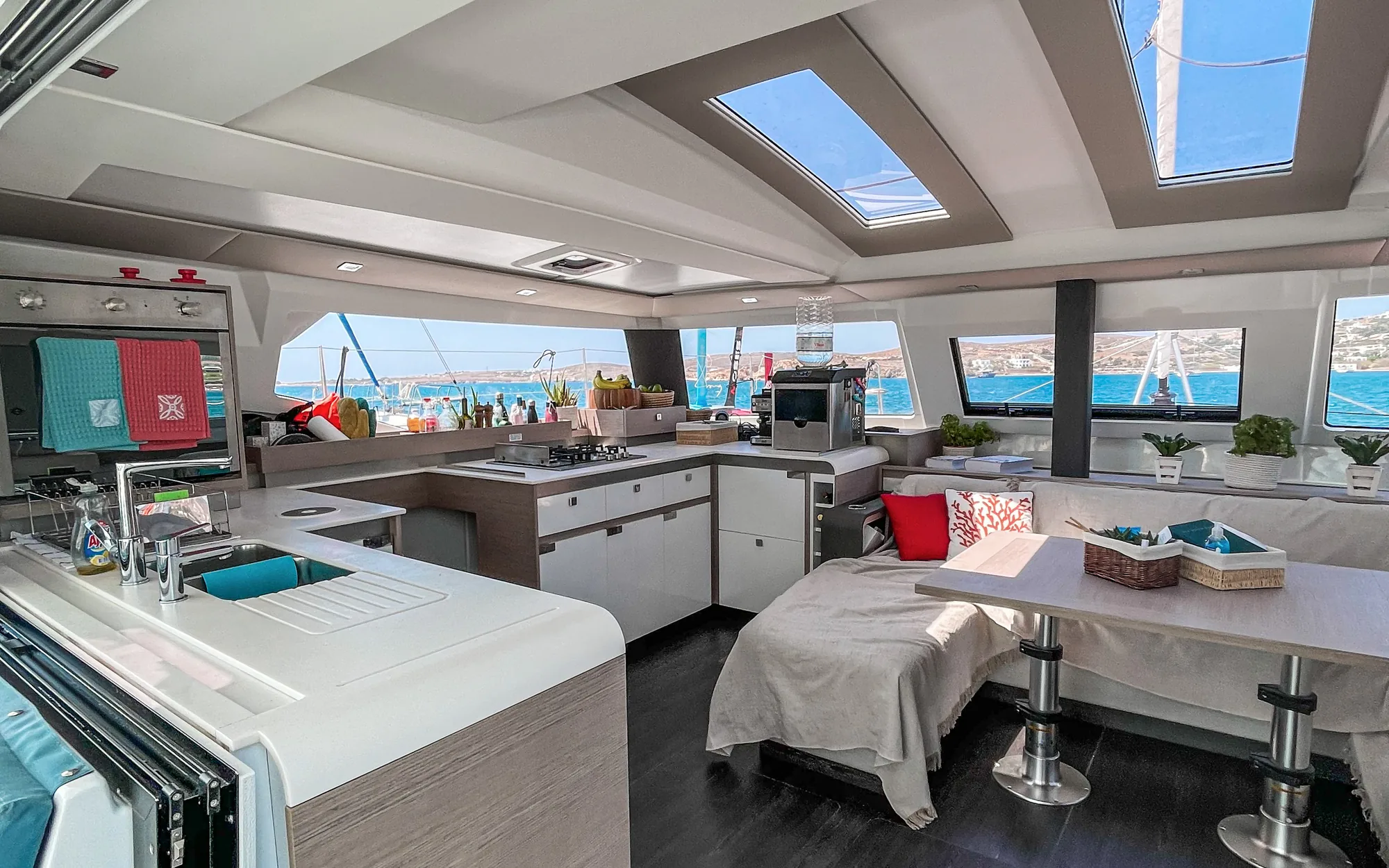 Bright open galley and saloon inside the Makani catamaran, with the sea through the windows.