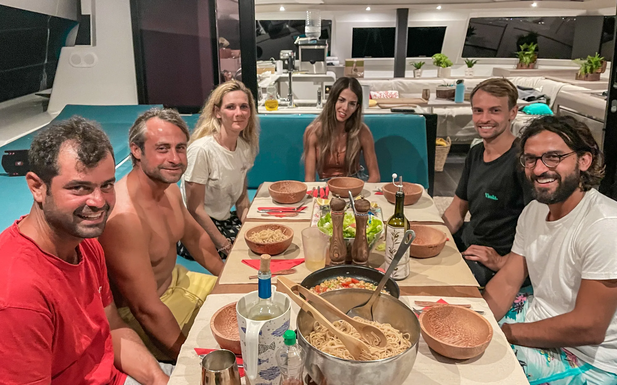 The whole group sharing a fresh dinner around the table in the Makani saloon at night.
