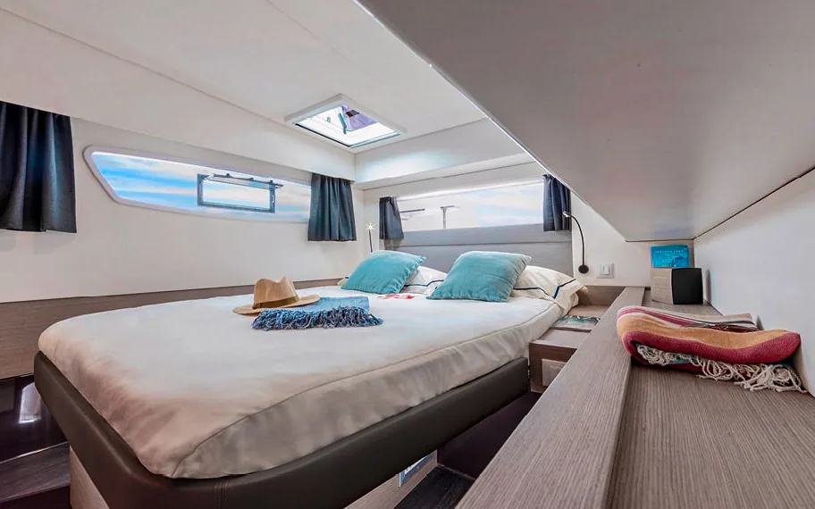 A private guest cabin aboard Makani, with a made-up double bed and its own hull windows.
